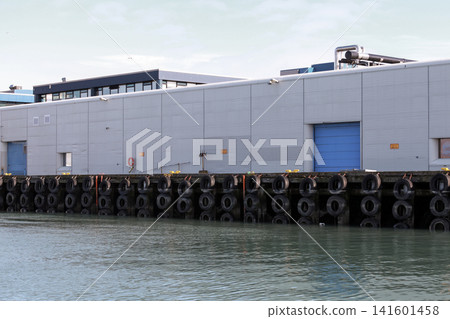 A corrugated metal warehouse sits on an industrial pier A corrugated metal warehouse sits on an industrial pier 141601458