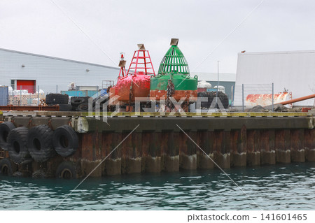 Two large red and green navigation buoys sit on a weathered industrial dock Two large red and green navigation buoys sit on a weathered industrial dock 141601465