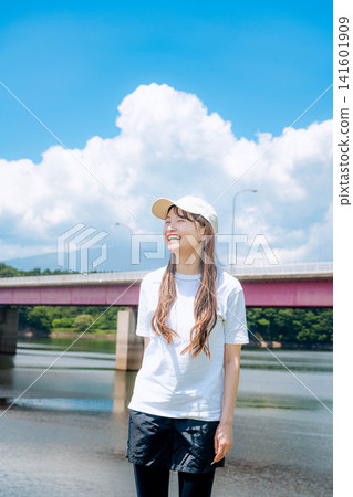 一位女子站在夏日的天空和一座紅色的橋前。 一位女子站在夏日的天空和一座紅色的橋前。 141601909