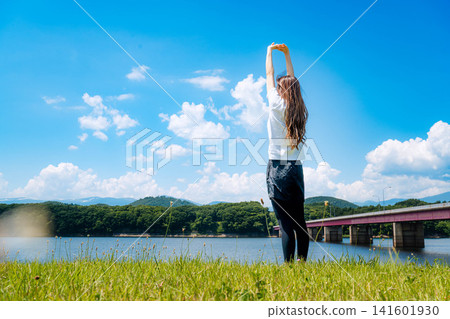 A woman stretching in a summer meadow. A woman stretching in a summer meadow. 141601930