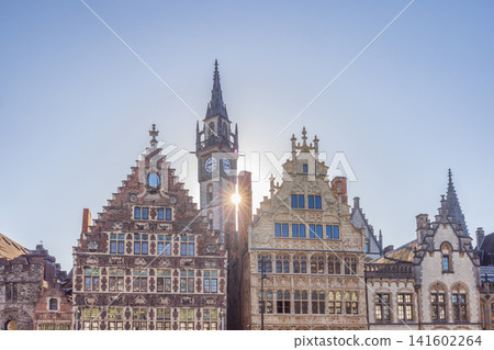 Ghent town in Belgium, Europe. Historic European city skyline with ancient architecture, bell tower, and a bright sunburst against a clear blue sky Ghent town in Belgium, Europe. Historic European city skyline with ancient architecture, bell tower, and a bright sunburst against a clear blue sky 141602264