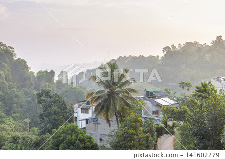 Lush Tropical Hills and Serene Dwellings at Dawn, a Picturesque Landscape Bathed in Soft Morning Light, Capturing Natural Beauty. Kandy town in Sri Lanka. Lush Tropical Hills and Serene Dwellings at Dawn, a Picturesque Landscape Bathed in Soft Morning Light, Capturing Natural Beauty. Kandy town in Sri Lanka. 141602279
