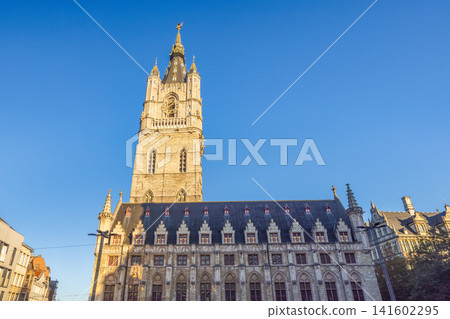 Ghent town in Belgium, Europe. Grand historic architecture with a Belfry tower against a clear blue sky, showcasing medieval European design and intricate details 141602295