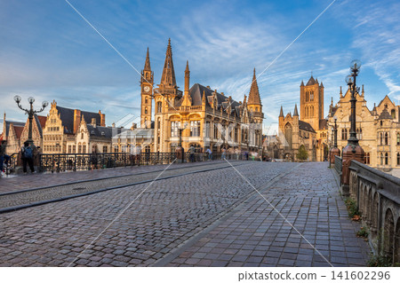 Ghent town in Belgium, Europe. View from St. Michael's Bridge. Historic city square with ancient architecture, cobblestone street, and clear blue sky in an old European town Ghent town in Belgium, Europe. View from St. Michael's Bridge. Historic city square with ancient architecture, cobblestone street, and clear blue sky in an old European town 141602296