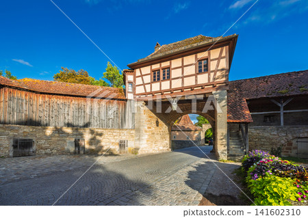 Rothenburg ob der Tauber, medieval old town in region of Bavaria in Germany, Europe. Historic half-timbered building with stone archway and cobblestone street on a sunny day Rothenburg ob der Tauber, medieval old town in region of Bavaria in Germany, Europe. Historic half-timbered building with stone archway and cobblestone street on a sunny day 141602310