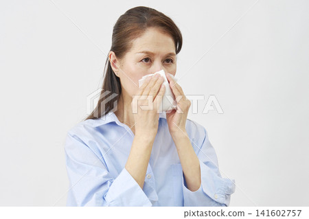 Woman blowing her nose on white background Woman blowing her nose on white background 141602757