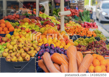 Colorful display of fresh fruit, vegetables and pumpkins arranged at an outdoor market stall. Seasonal produce, organic farm apples, pears, oranges, grape, squash. Autumn harvest Colorful display of fresh fruit, vegetables and pumpkins arranged at an outdoor market stall. Seasonal produce, organic farm apples, pears, oranges, grape, squash. Autumn harvest 141602850