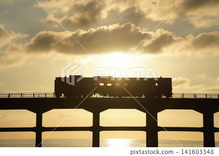 A local train on the San'in Main Line crosses the Sōgōgawa Bridge with the setting sun at its back. A local train on the San'in Main Line crosses the Sōgōgawa Bridge with the setting sun at its back. 141603348