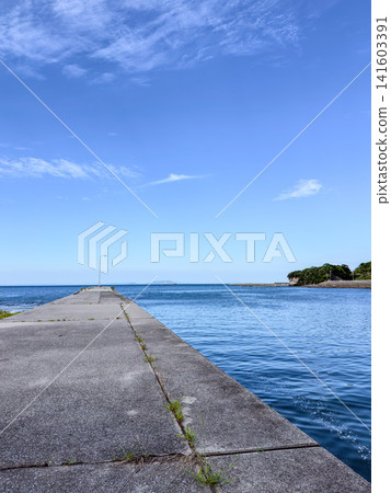 A concrete breakwater stretches across the summer blue sky and calm sea. A concrete breakwater stretches across the summer blue sky and calm sea. 141603391