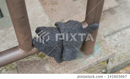 Gray wool glove on metal railing outdoors Gray wool glove on metal railing outdoors 141603667