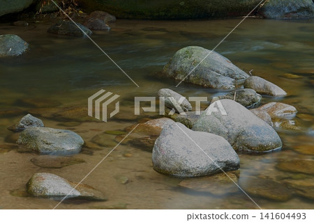 山澗溪流中聳立著巨石,水流平緩。 山澗溪流中聳立著巨石,水流平緩。 141604493