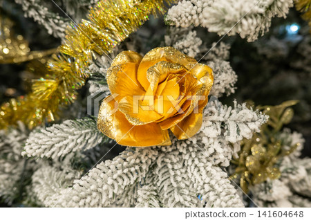 Golden rose ornament on snow-dusted christmas tree branches Golden rose ornament on snow-dusted christmas tree branches 141604648