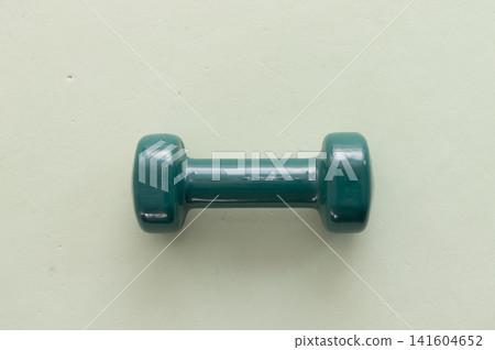 Single green dumbbell on light background for fitness and strength training Single green dumbbell on light background for fitness and strength training 141604652