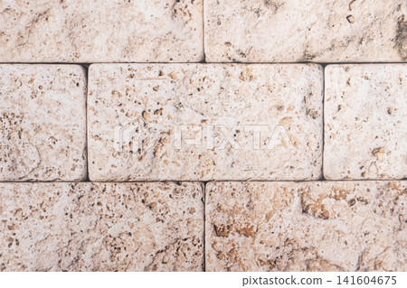 Beige stone tiles displaying textured travertine wall surface Beige stone tiles displaying textured travertine wall surface 141604675