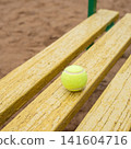 Tennis ball on weathered yellow wooden bench outdoors 141604716