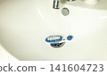 Bathroom sink with blue and white scrub brush in drain 141604723