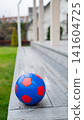 Blue and red soccer ball on wooden bench near green lawn 141604725