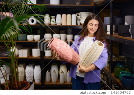 Woman customer chooses vases while exploring variety of flower pots in boutique Woman customer chooses vases while exploring variety of flower pots in boutique 141604792
