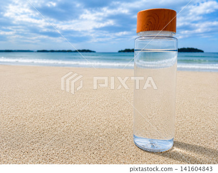 A reusable water bottle placed on a summer beach, representing hydration. A reusable water bottle placed on a summer beach, representing hydration. 141604843