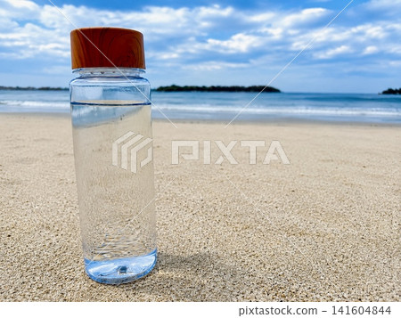 A summer beach scene with a reusable water bottle, evoking the idea of staying hydrated. A summer beach scene with a reusable water bottle, evoking the idea of staying hydrated. 141604844