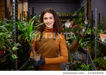 Female employee presenting potted plants amid warm retail environment Female employee presenting potted plants amid warm retail environment 141604949