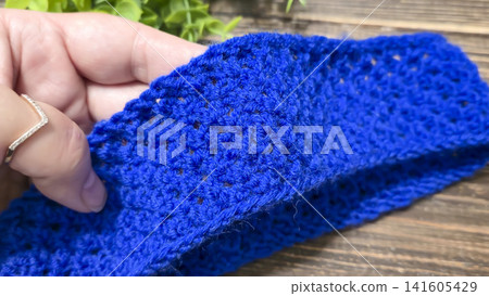 A blue thread pattern on a wooden background. Knitting tutorial and sample of the finished piece. A blue thread pattern on a wooden background. Knitting tutorial and sample of the finished piece. 141605429