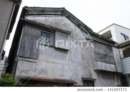 A vacant house with severely deteriorated mortar exterior walls and windows boarded up with plywood. A vacant house with severely deteriorated mortar exterior walls and windows boarded up with plywood. 141605571