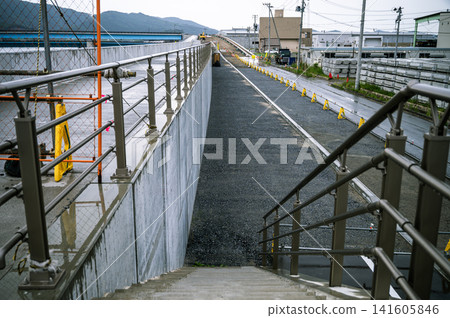 雨中，山頂的階梯上正在進行施工，這是一處新建混凝土海堤的施工現場。 141605846
