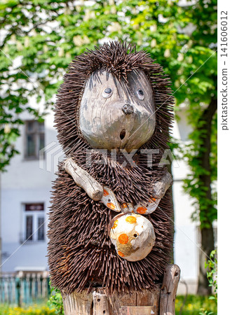 Wooden sculpture of hedgehog with knot-bag in green park during daytime. 05.12.2019. Kyiv. Ukraine Wooden sculpture of hedgehog with knot-bag in green park during daytime. 05.12.2019. Kyiv. Ukraine 141606012
