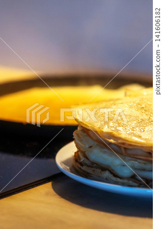 Stack of homemade crepes and frying pan 141606182