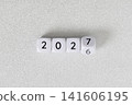 Year 2026 changing to 2027 on dice, glitter festive gray background. New year change concept 141606195