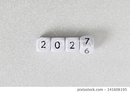 Year 2026 changing to 2027 on dice, glitter festive gray background. New year change concept 141606195