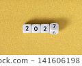 Year 2026 changing to 2027 on dice, glitter festive golden background. New year change concept 141606198