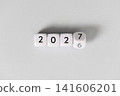 Year 2026 changing to 2027 on dice, gray background. New year change concept 141606201