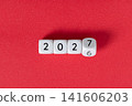 Year 2026 changing to 2027 on dice, glitter festive red background. New year change concept 141606203
