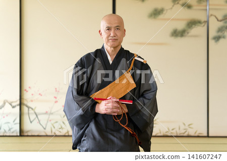A portrait of a monk sitting in a Japanese-style room, holding a folding fan and prayer beads. A portrait of a monk sitting in a Japanese-style room, holding a folding fan and prayer beads. 141607247