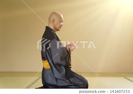 一位身著僧袍的僧侶的側面像，雙手合十祈禱。 141607253