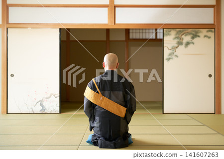 A monk in a袈裟 (kesa, Buddhist robe) is shown from behind, sitting in a formal kneeling position and meditating. A monk in a袈裟 (kesa, Buddhist robe) is shown from behind, sitting in a formal kneeling position and meditating. 141607263