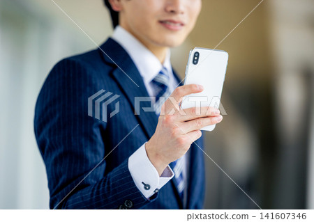 在辦公室操作智能手機的年輕人 在辦公室操作智能手機的年輕人 141607346