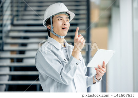 A young man wearing work clothes 141607635