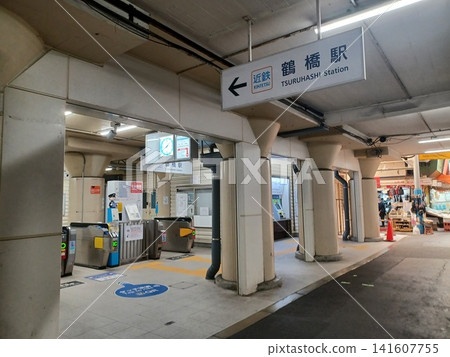 The station square walkway shows the ticket gates on the left and a shopping street extending to the right. The station square walkway shows the ticket gates on the left and a shopping street extending to the right. 141607755
