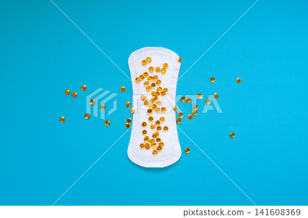 Sanitary Pad with Gold Sequins Representing Urinary Leakage on Blue Background Sanitary Pad with Gold Sequins Representing Urinary Leakage on Blue Background 141608369