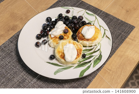 Traditional cottage cheese pancakes syrniki served with fresh blueberries and sour cream Traditional cottage cheese pancakes syrniki served with fresh blueberries and sour cream 141608900