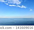 一艘孤零零的船漂浮在浩瀚的海洋上，背景是蔚藍的天空。地平線影像，風景，庫存照片。晴空萬裡。 141609016