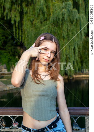 Teen girl portrait on a bridge in a park with willow trees and casual summer style Teen girl portrait on a bridge in a park with willow trees and casual summer style 141609562