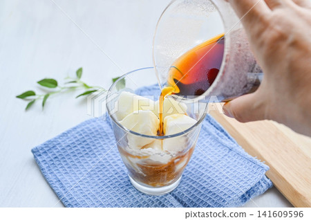 Iced café au lait made by pouring coffee over homemade milk ice. Iced café au lait made by pouring coffee over homemade milk ice. 141609596