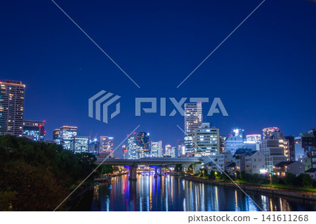 大阪大川的夜景:摩天大樓的霓虹燈和燈光在水面上閃閃發光。 大阪大川的夜景:摩天大樓的霓虹燈和燈光在水面上閃閃發光。 141611268