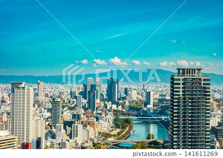 An aerial-style panoramic view of Osaka city, with skyscrapers and the Okawa River stretching across the blue sky. An aerial-style panoramic view of Osaka city, with skyscrapers and the Okawa River stretching across the blue sky. 141611269