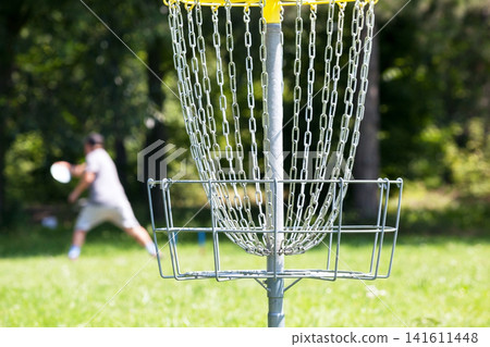 Man throwing frisbee playing disc golf in the park 141611448