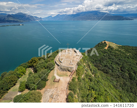 Drone view of the Manerba Cross and summit ruins on the wooded Rocca above Lake Garda Drone view of the Manerba Cross and summit ruins on the wooded Rocca above Lake Garda 141611720